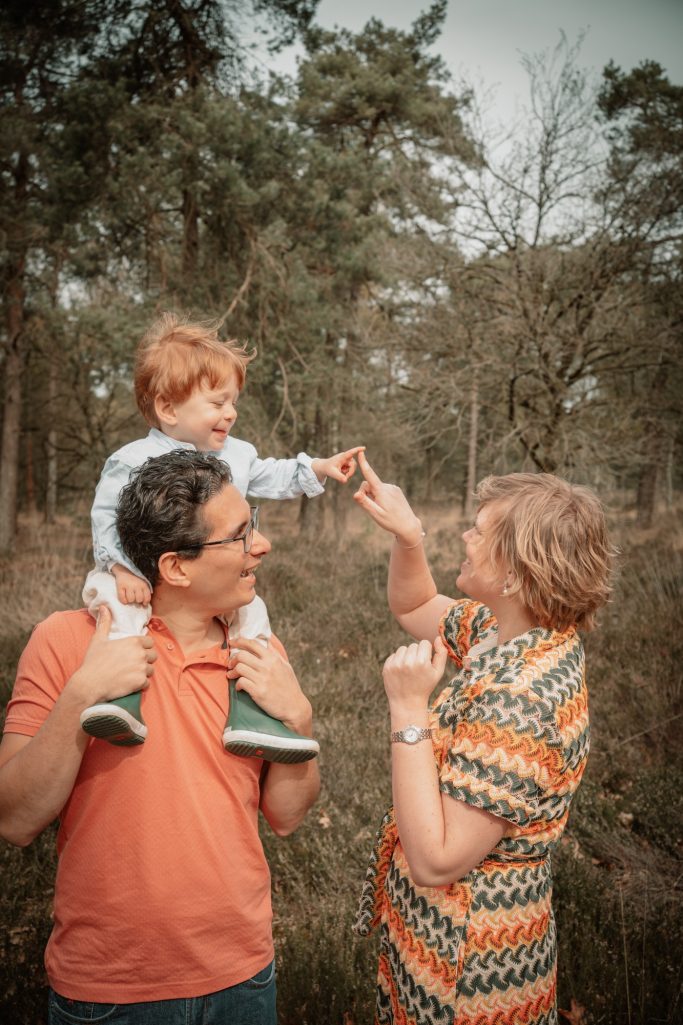 Spelen met papa en mama in het bos tijdens een gezinsfotoshoot.